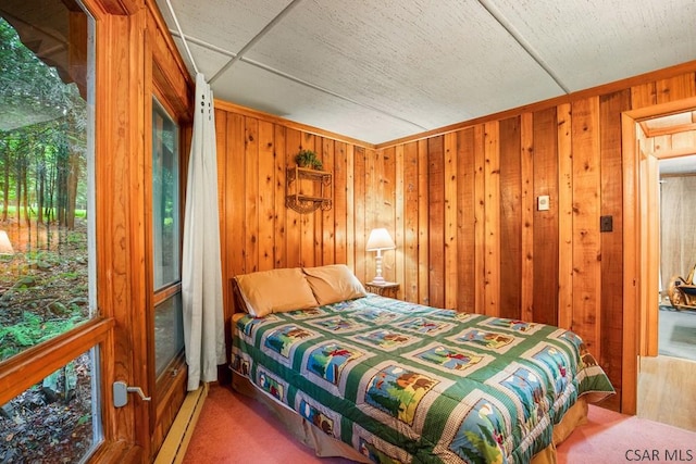 carpeted bedroom featuring a drop ceiling, wooden walls, and baseboard heating