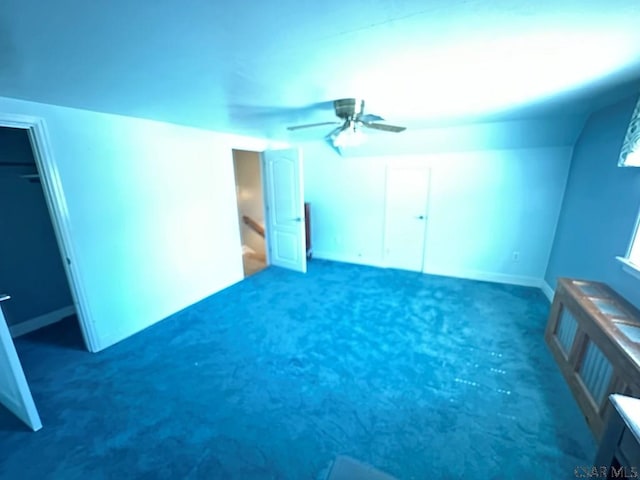 additional living space with ceiling fan and dark carpet