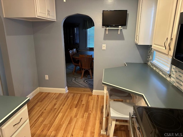 kitchen with white cabinetry, light wood-type flooring, and electric stove