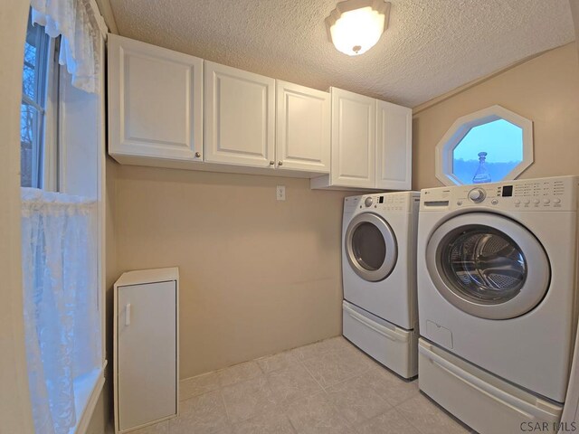 laundry area featuring cabinets, washing machine and clothes dryer, and a textured ceiling