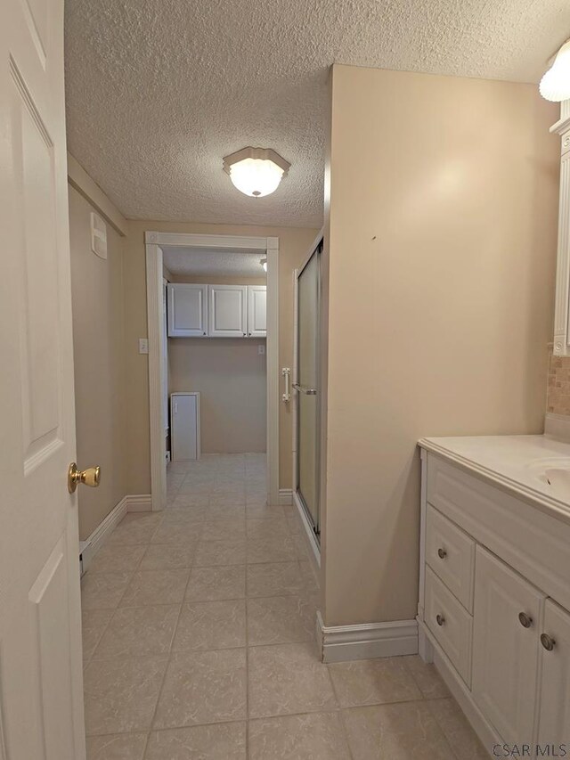 bathroom with vanity, a textured ceiling, and walk in shower