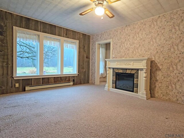 unfurnished living room with a baseboard radiator, carpet flooring, ceiling fan, and a fireplace