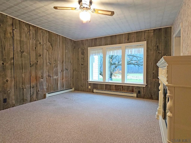 unfurnished room featuring wooden walls, carpet, ceiling fan, and baseboard heating