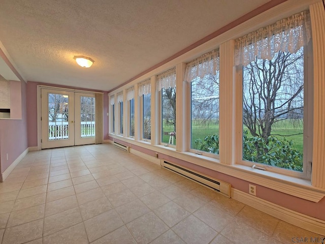 unfurnished sunroom with plenty of natural light, a baseboard heating unit, and french doors