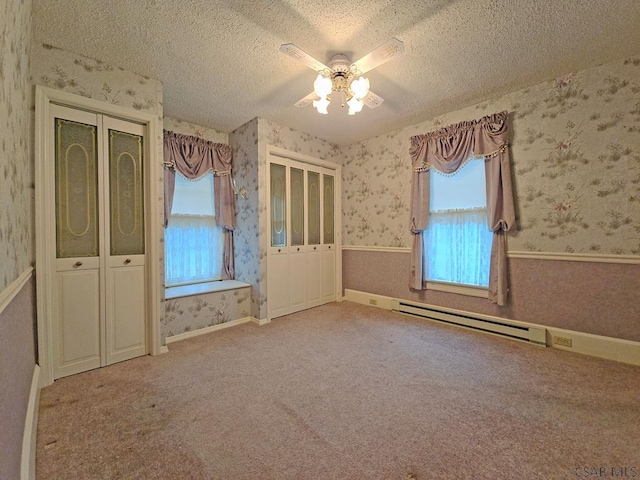 carpeted spare room with a baseboard heating unit, a textured ceiling, and ceiling fan