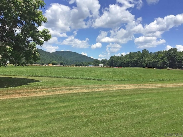 view of property's community featuring a rural view, a mountain view, and a yard