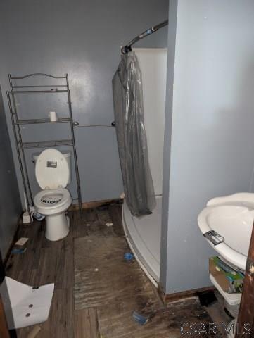 bathroom featuring walk in shower, toilet, and hardwood / wood-style flooring