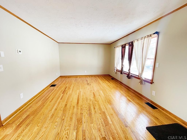 spare room with crown molding, a textured ceiling, and light hardwood / wood-style flooring