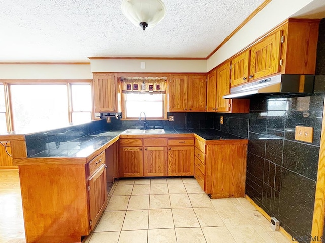 kitchen with sink, light tile patterned floors, ornamental molding, a textured ceiling, and kitchen peninsula