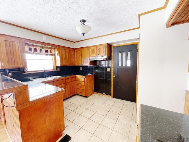 kitchen with sink, light tile patterned floors, kitchen peninsula, crown molding, and a textured ceiling