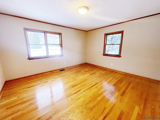 unfurnished room featuring crown molding and light wood-type flooring