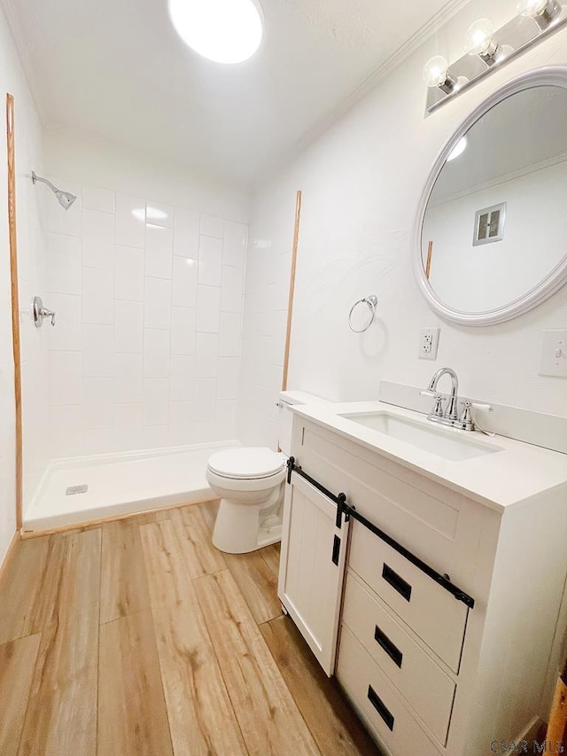 bathroom with vanity, hardwood / wood-style floors, toilet, and a tile shower