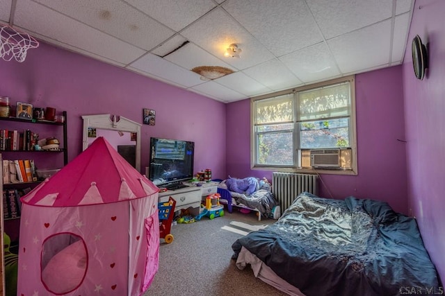 bedroom with radiator, carpet floors, and a drop ceiling