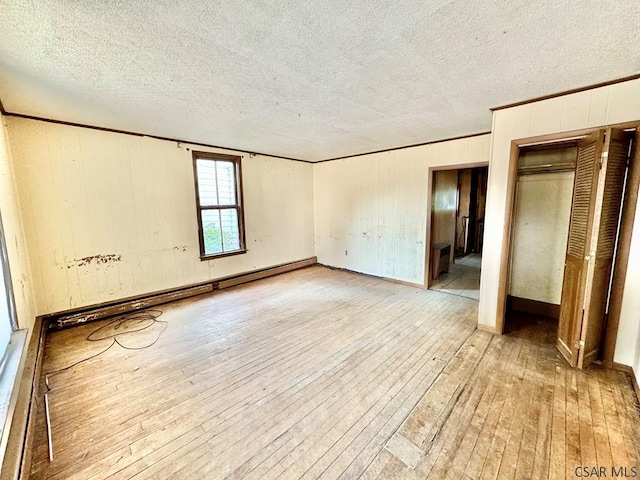 unfurnished room featuring ornamental molding, light hardwood / wood-style flooring, and a baseboard heating unit