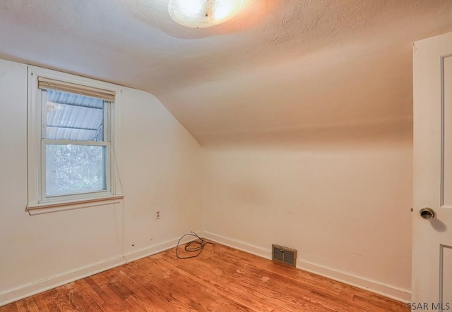 bonus room with lofted ceiling and light wood-type flooring