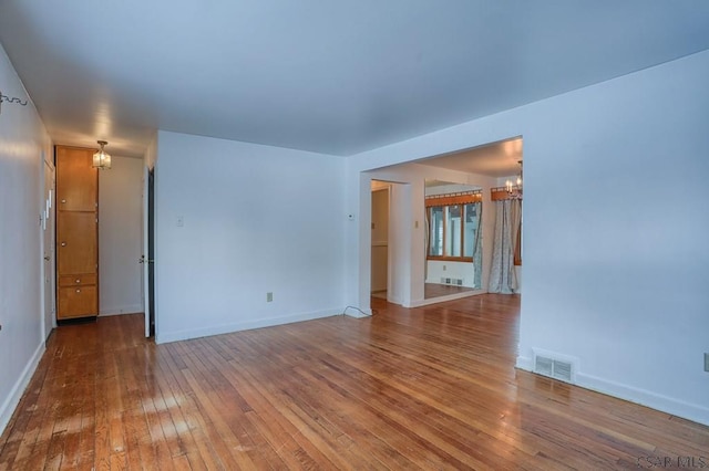 unfurnished room featuring a notable chandelier and hardwood / wood-style flooring