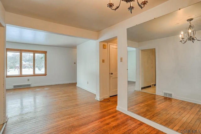 unfurnished room featuring a chandelier and light wood-type flooring