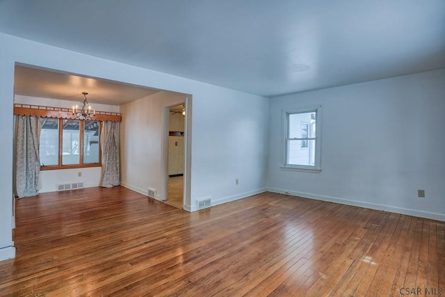 empty room featuring an inviting chandelier and wood-type flooring