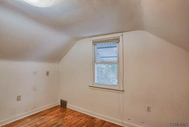 bonus room with hardwood / wood-style flooring, lofted ceiling, and a textured ceiling