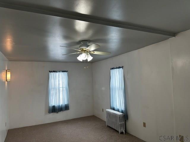 carpeted empty room featuring radiator and ceiling fan