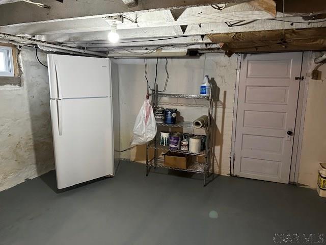 below grade area featuring freestanding refrigerator