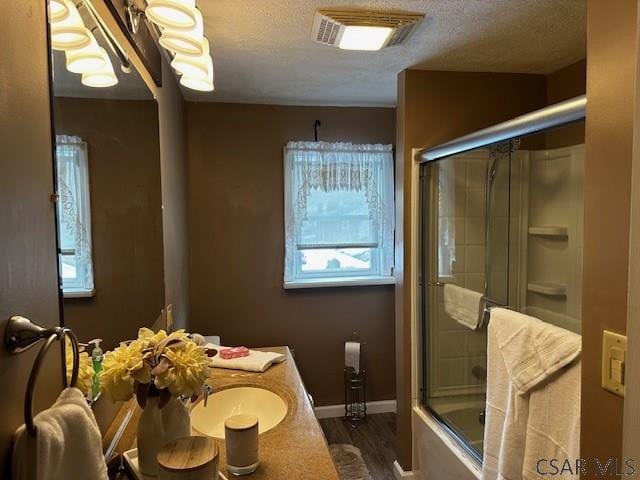 full bath with enclosed tub / shower combo, a textured ceiling, wood finished floors, vanity, and visible vents