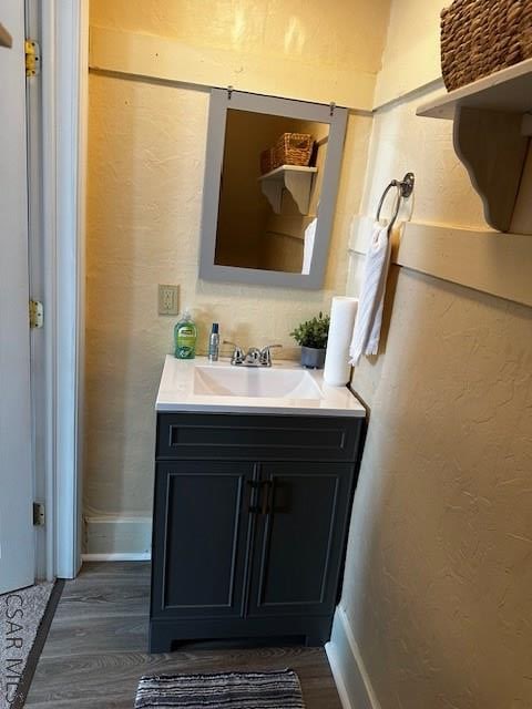 bathroom with vanity, wood finished floors, and a textured wall