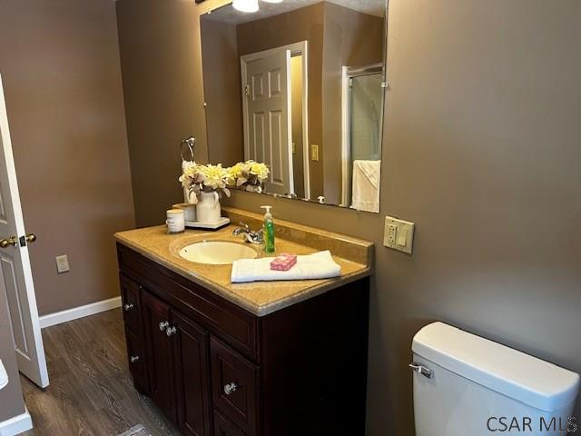 bathroom with baseboards, vanity, toilet, and wood finished floors