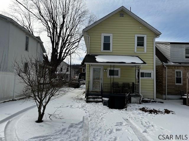 snow covered back of property with a porch