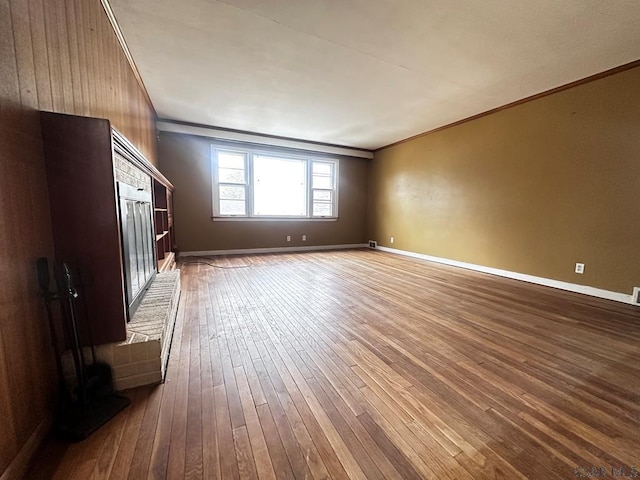 unfurnished living room featuring ornamental molding, dark wood-style flooring, and baseboards