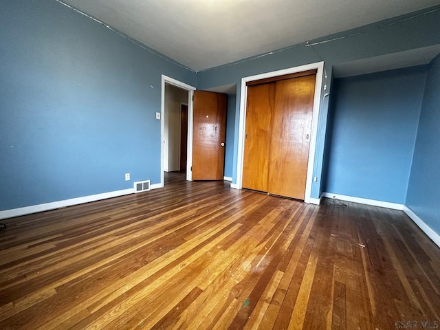 unfurnished bedroom featuring a closet, baseboards, visible vents, and hardwood / wood-style floors