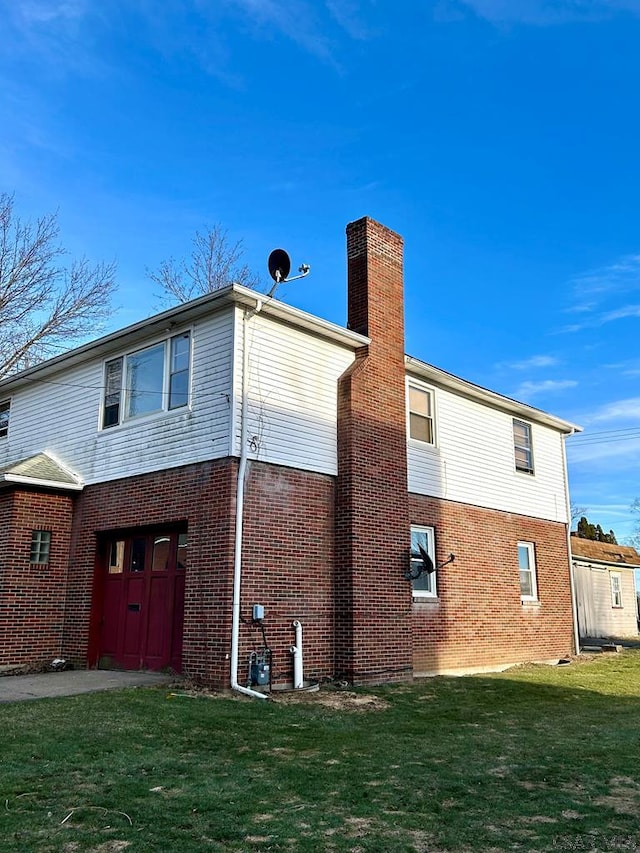 rear view of house with a yard, brick siding, and a chimney