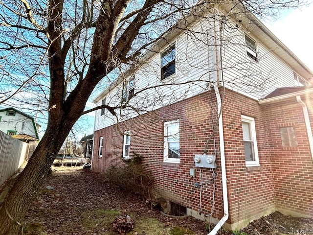 view of property exterior with fence and brick siding