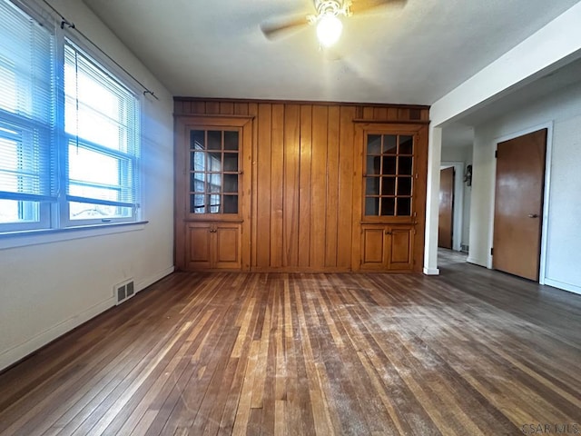 empty room featuring baseboards, hardwood / wood-style flooring, visible vents, and a ceiling fan