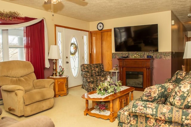 living room with ceiling fan, light colored carpet, plenty of natural light, and a textured ceiling