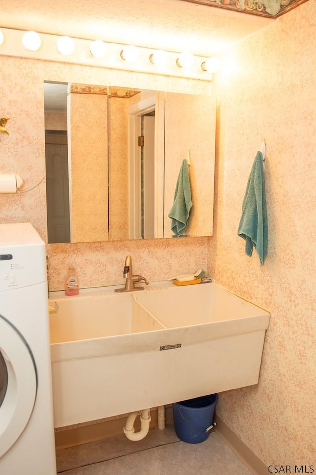 bathroom with washer / clothes dryer, sink, and tile patterned flooring