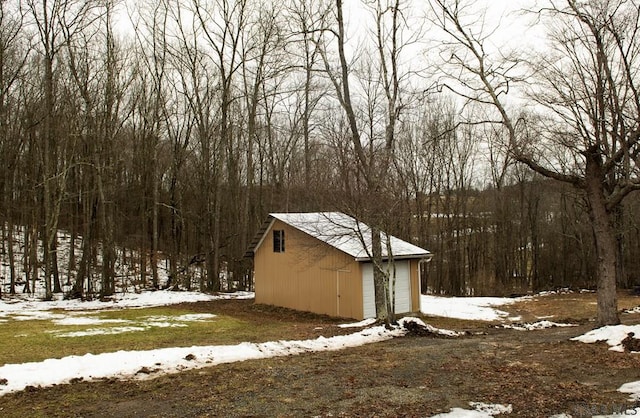 snowy yard with a garage and an outdoor structure