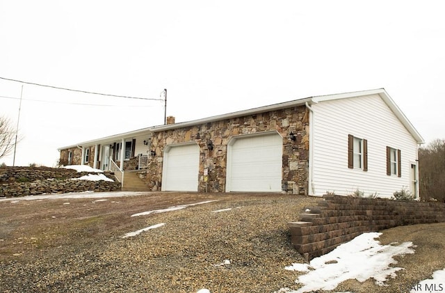 view of snowy exterior featuring a garage and covered porch