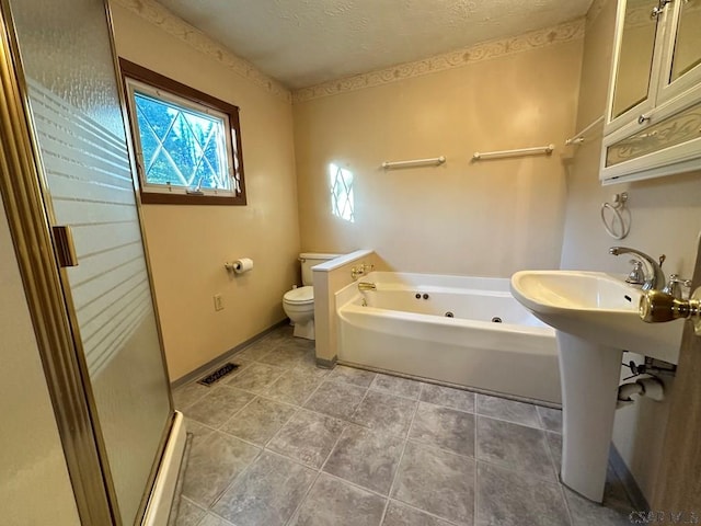 bathroom featuring a bathing tub, sink, a textured ceiling, and toilet