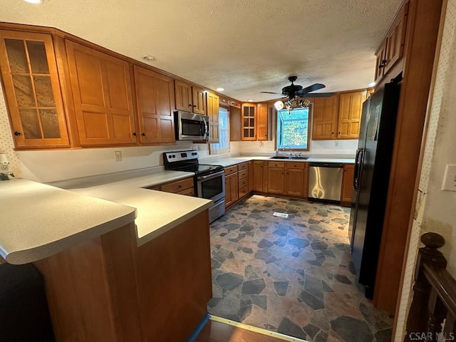 kitchen with sink, a textured ceiling, kitchen peninsula, ceiling fan, and stainless steel appliances