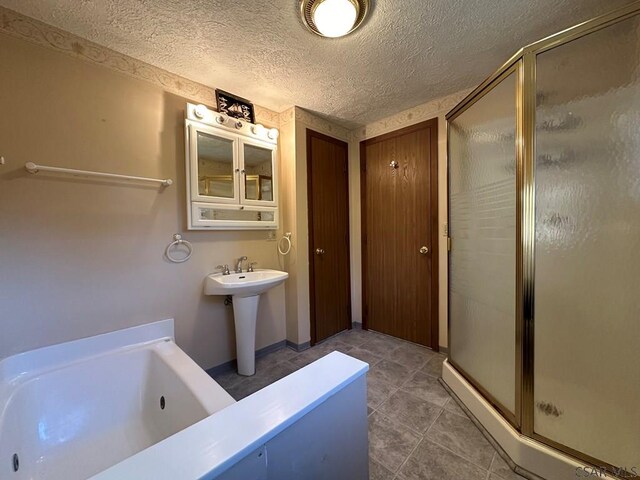 bathroom featuring independent shower and bath, sink, and a textured ceiling