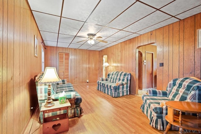 living room featuring ceiling fan and wood walls