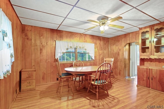 dining room featuring light hardwood / wood-style floors, ceiling fan, and wood walls