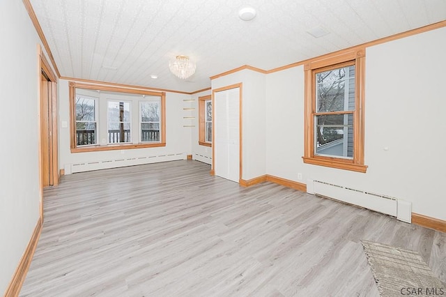 unfurnished room with light wood-style floors, a baseboard heating unit, and crown molding