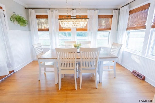 dining space featuring visible vents, light wood-style floors, wainscoting, and a notable chandelier