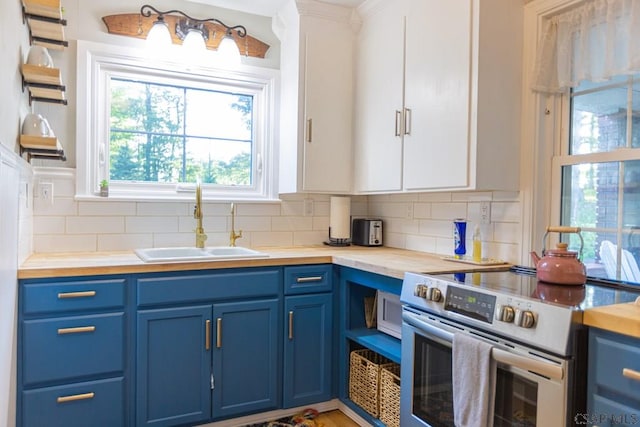 kitchen with decorative backsplash, blue cabinetry, wooden counters, and electric stove