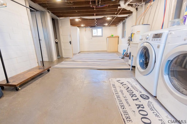 laundry area featuring washing machine and clothes dryer, concrete block wall, and laundry area
