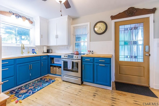 kitchen with electric range, ceiling fan, a sink, white microwave, and blue cabinets