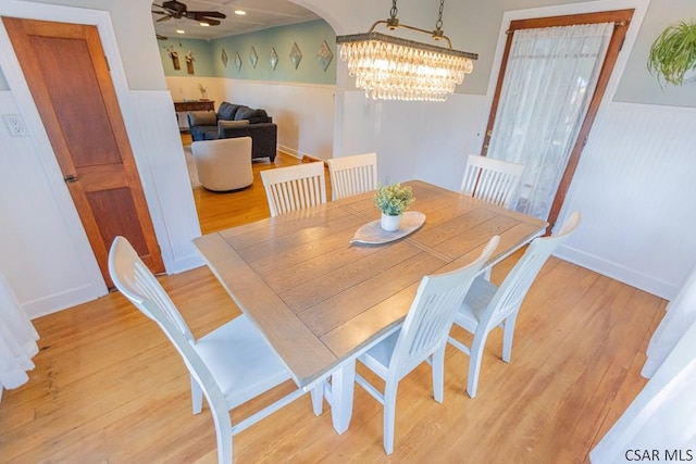 dining room with light wood-style floors, wainscoting, and a notable chandelier
