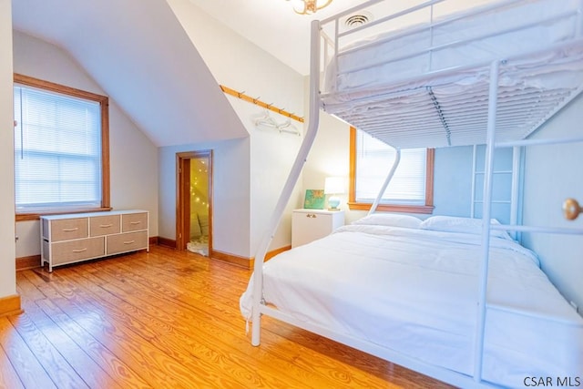 bedroom featuring baseboards, lofted ceiling, wood finished floors, and multiple windows